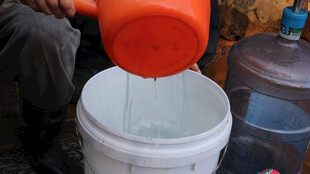 橙色容器向白桶倒水场景